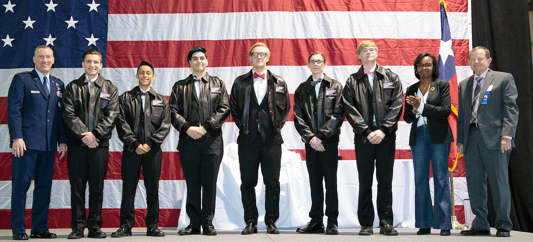 nine people standing in front of American flag accepting an award