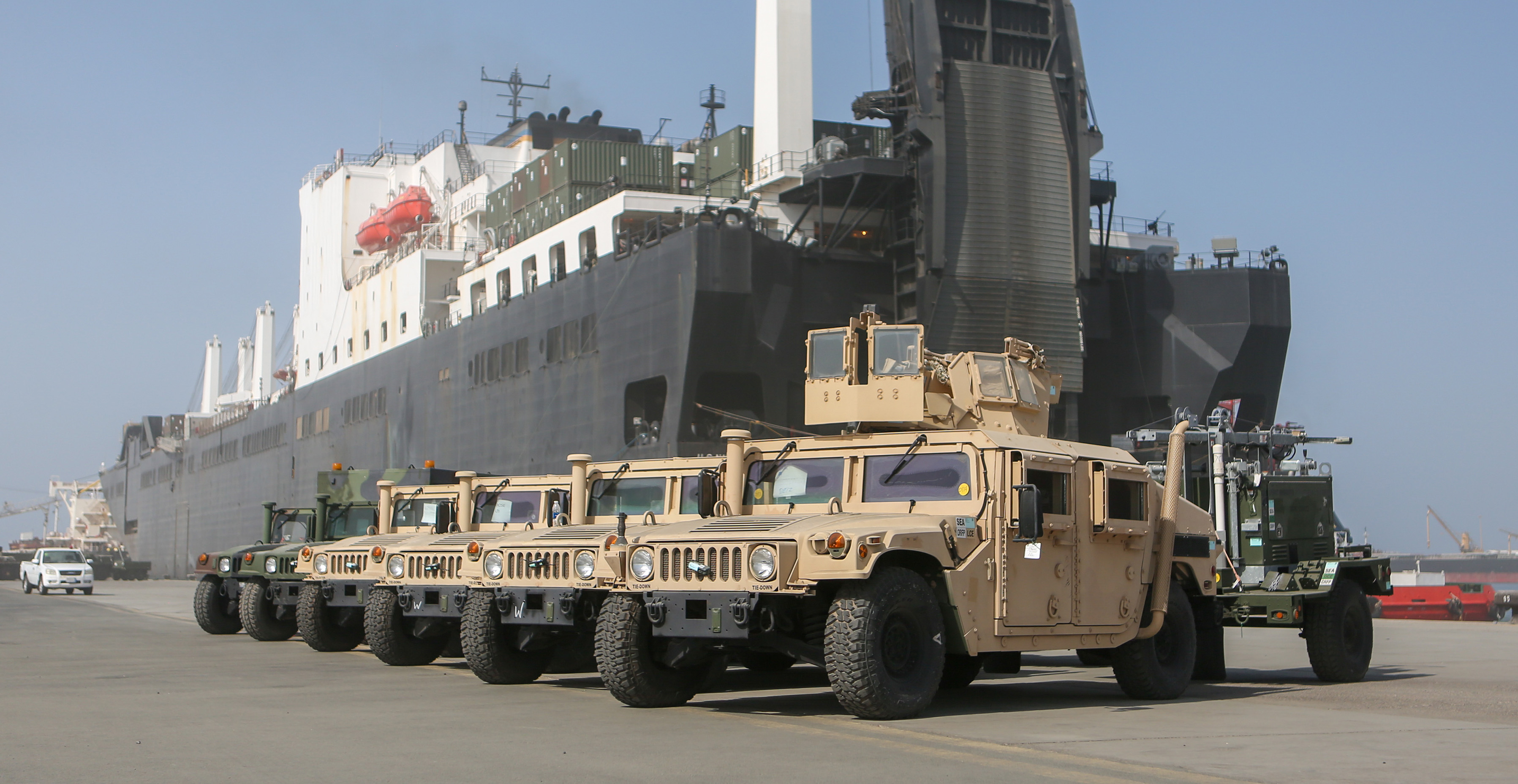 Marine Corps equipment on dock near a transport ship