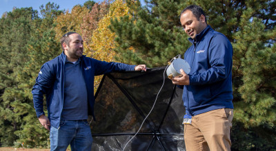 Two researchers outdoors setting up umbrella like device.